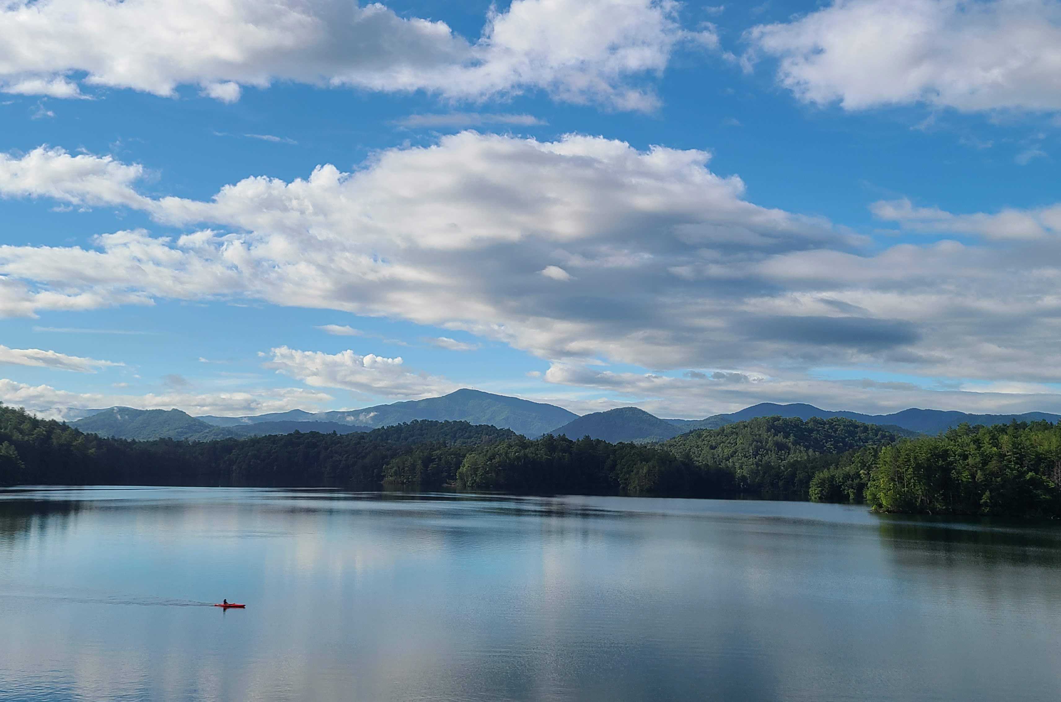 Sky reflects onto full lake surrounded by mountains